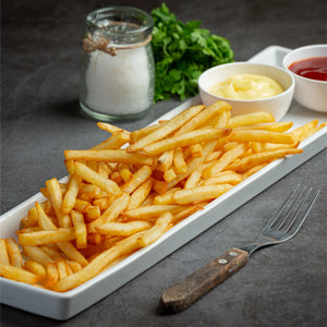 Crispy French fries on a white plate with ketchup, mayo, salt, and fresh parsley, plant-based food.
