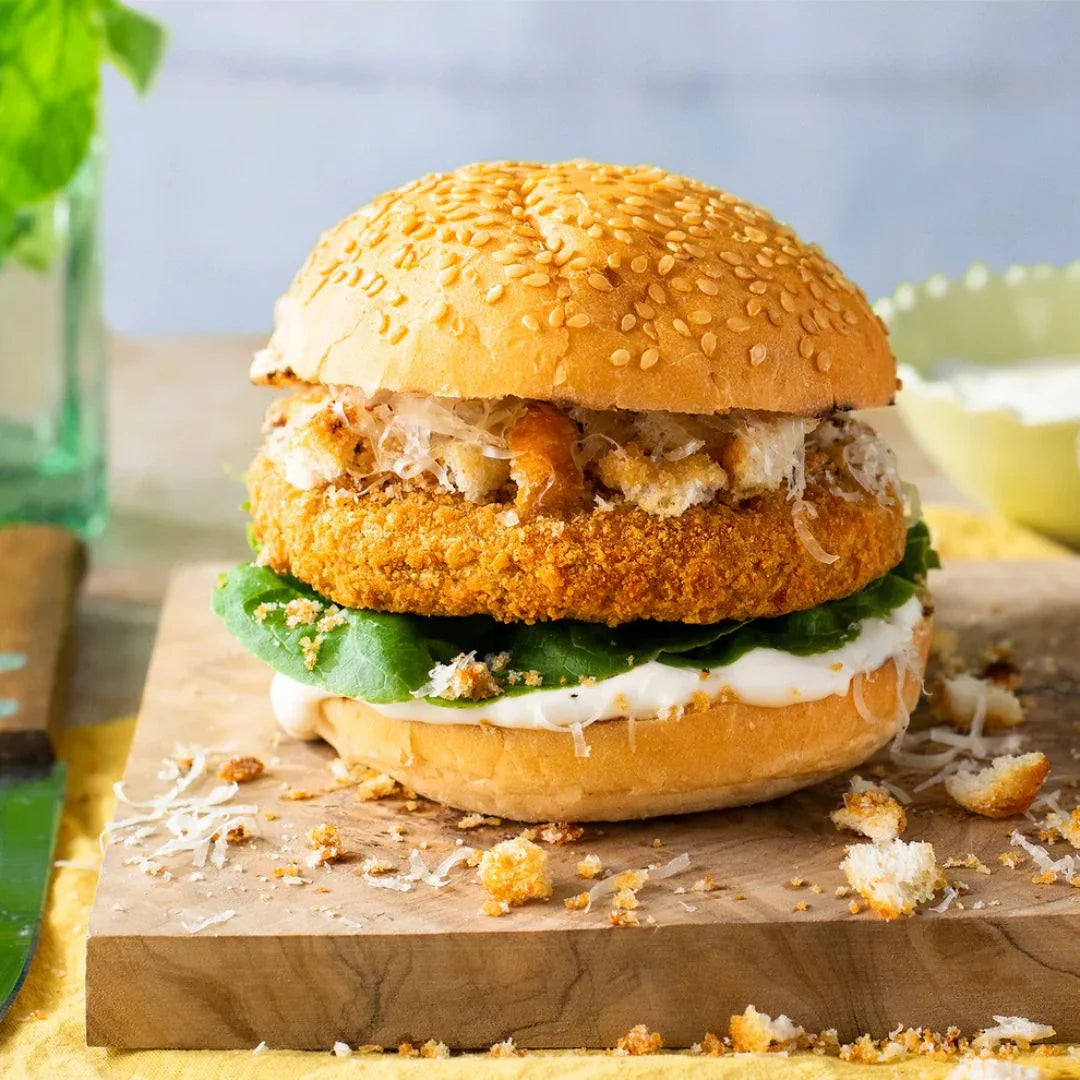 Crispy plant-based burger with lettuce, vegan mayo, and sesame seed bun on wooden board