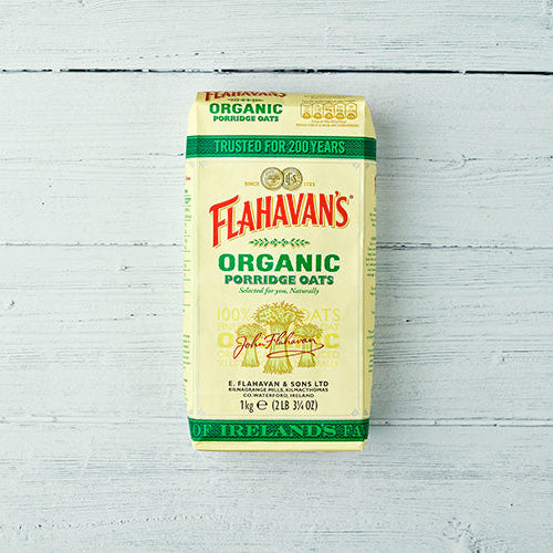 Flahavan's Organic Porridge Oats 1kg pack on a white wooden background, plant-based food