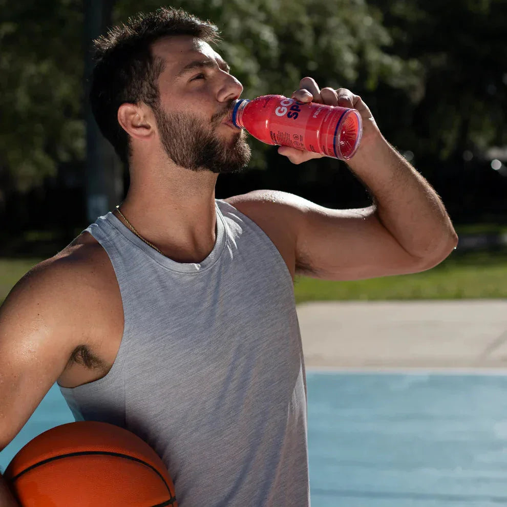 Man on outdoor basketball court drinking GoodSport Fruit Punch plant-based beverage