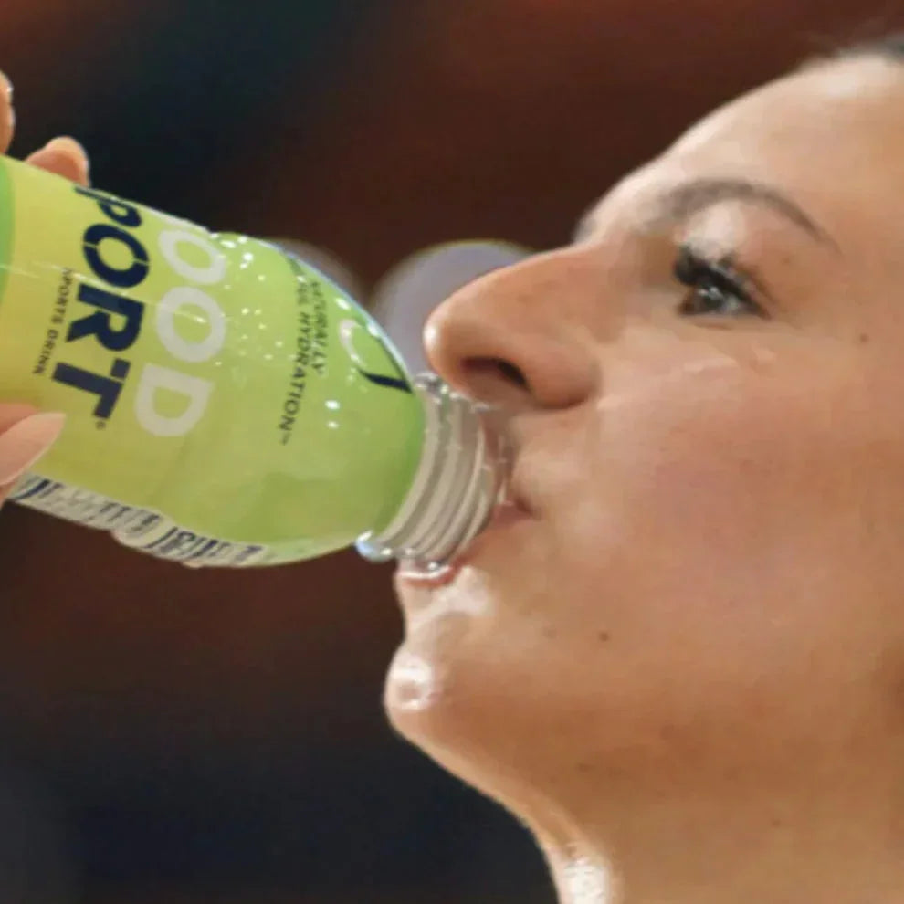 Woman drinking GoodSport Lemon Lime sports drink, plant-based hydration, active lifestyle.