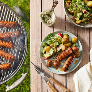 Grilled plant-based sausages on a barbecue and served with potato salad on a wooden table