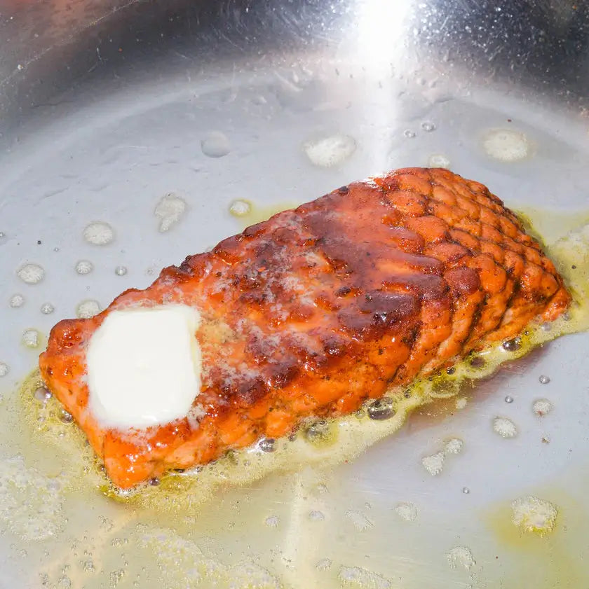 Salmon fillet cooking in a pan with butter