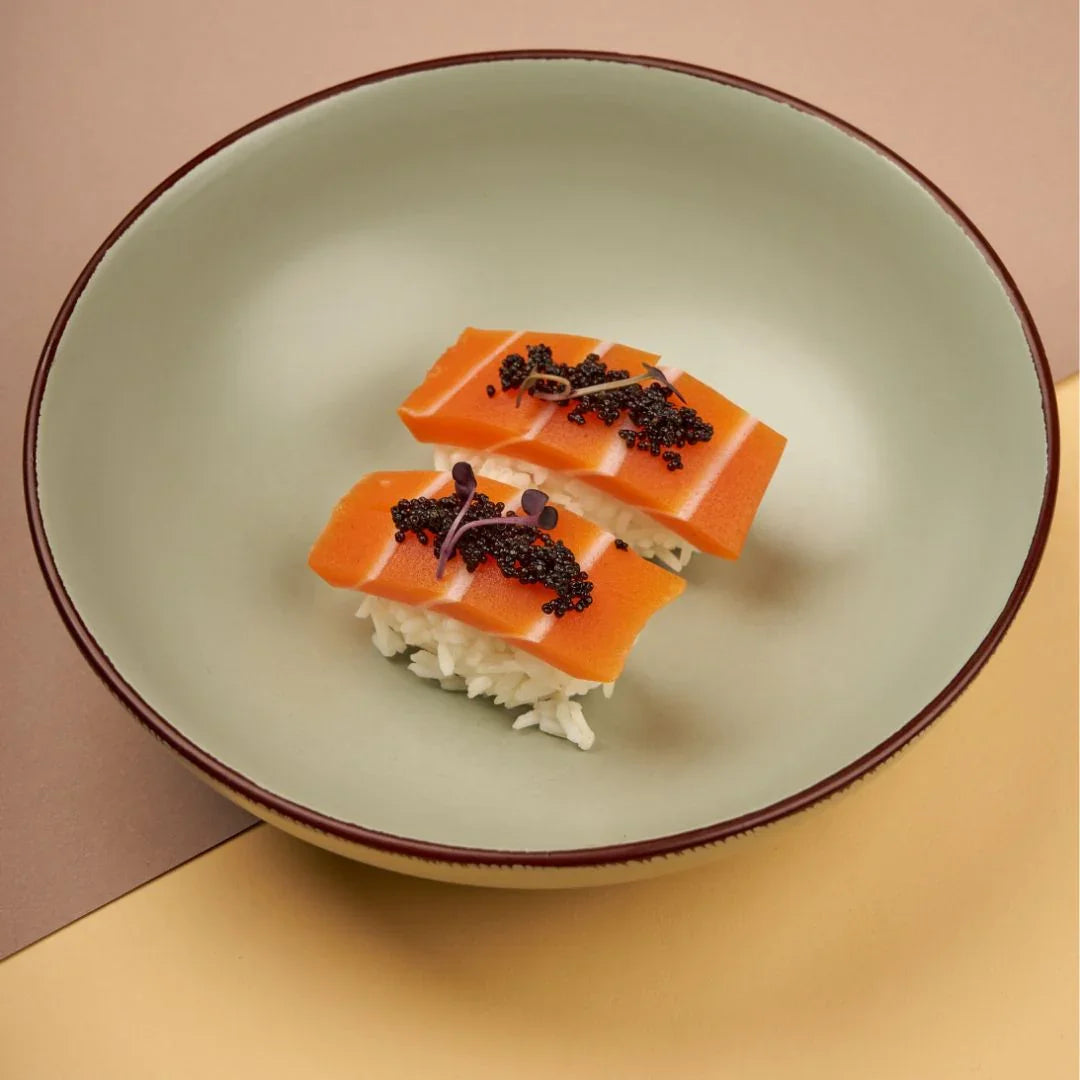 Plant-based salmon sashimi nigiri with rice and garnish on a beige plate, iPlantBased UAE