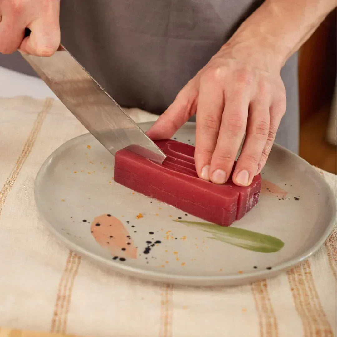 Hand slicing plant-based sashimi block on a decorated plate, iPlantBased UAE vegan food