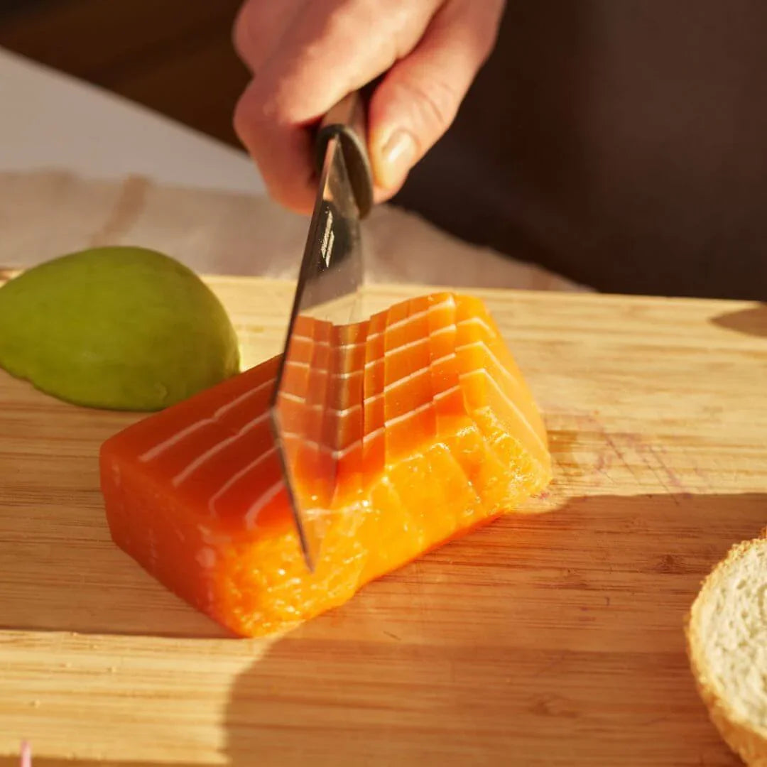 Hand slicing plant-based salmon sashimi block on wooden board, vegan seafood by iPlantBased UAE