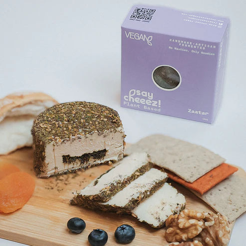 Plant-based zaatar vegan cheese wheel sliced on a board with bread, nuts, and fruit, iPlantBased UAE