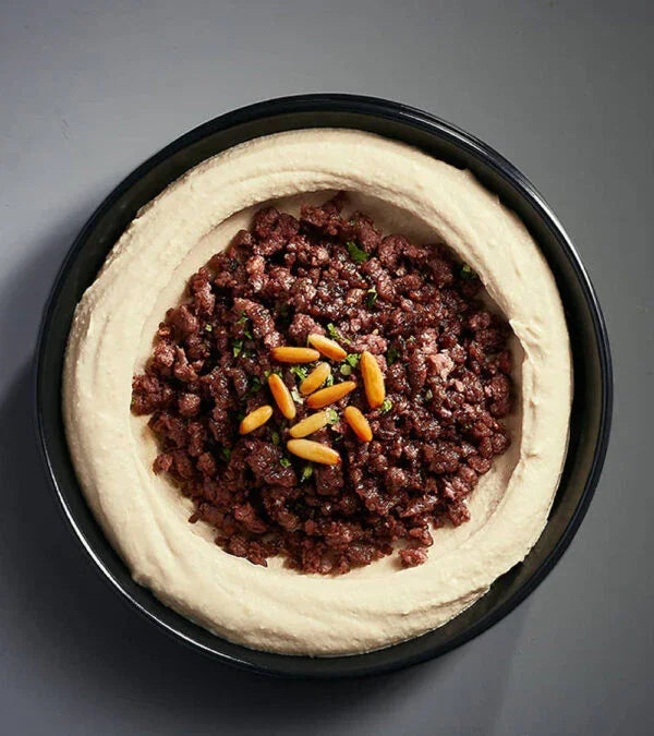 Plant-based hummus with vegan minced topping and pine nuts in a black bowl, iPlantBased UAE
